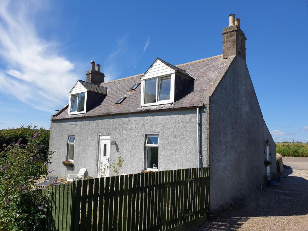 a white house with a fence in front of it at West Gallaton Farmhouse in Stonehaven