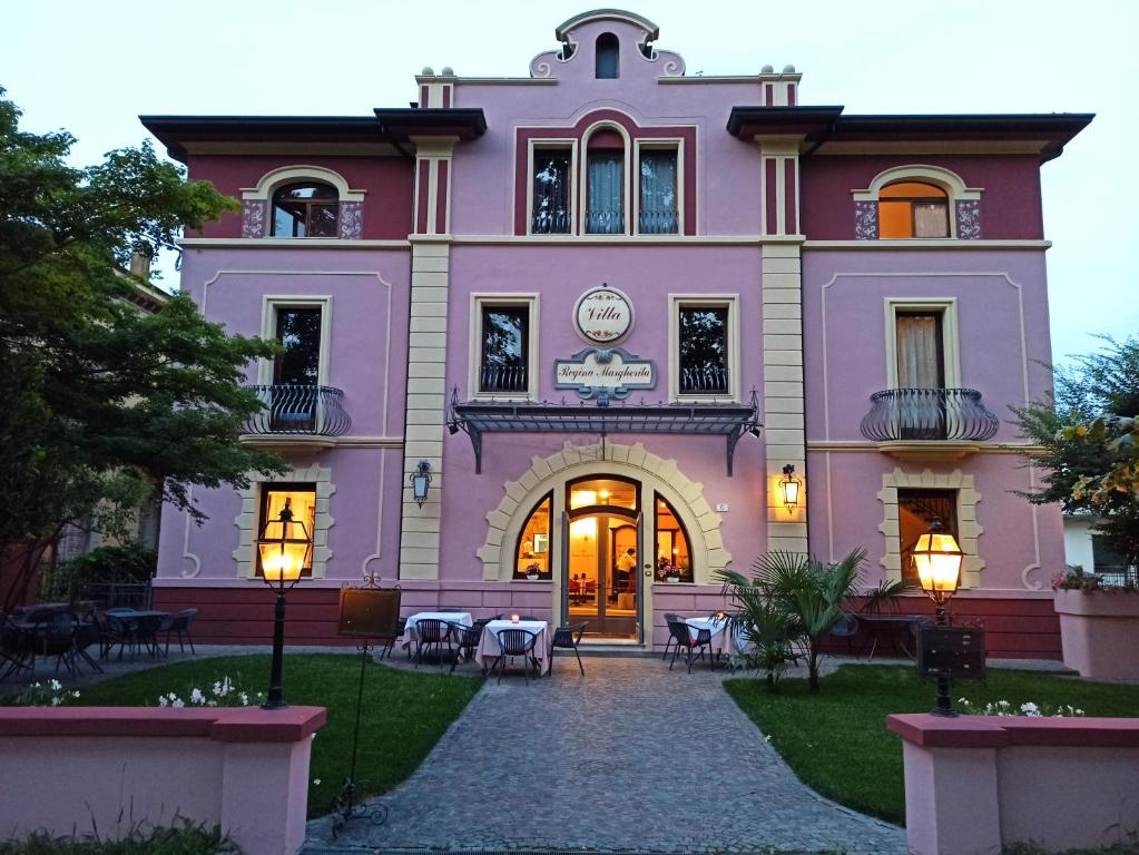 un edificio rosa con tavoli e sedie di fronte di Villa Regina Margherita a Rovigo