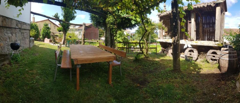 une table en bois et un banc dans une cour dans l'établissement Casa do Horreo, à Puentecesures