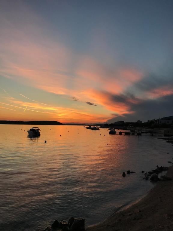 a sunset over a body of water with boats in it at Apartments Maria Rab in Barbat na Rabu
