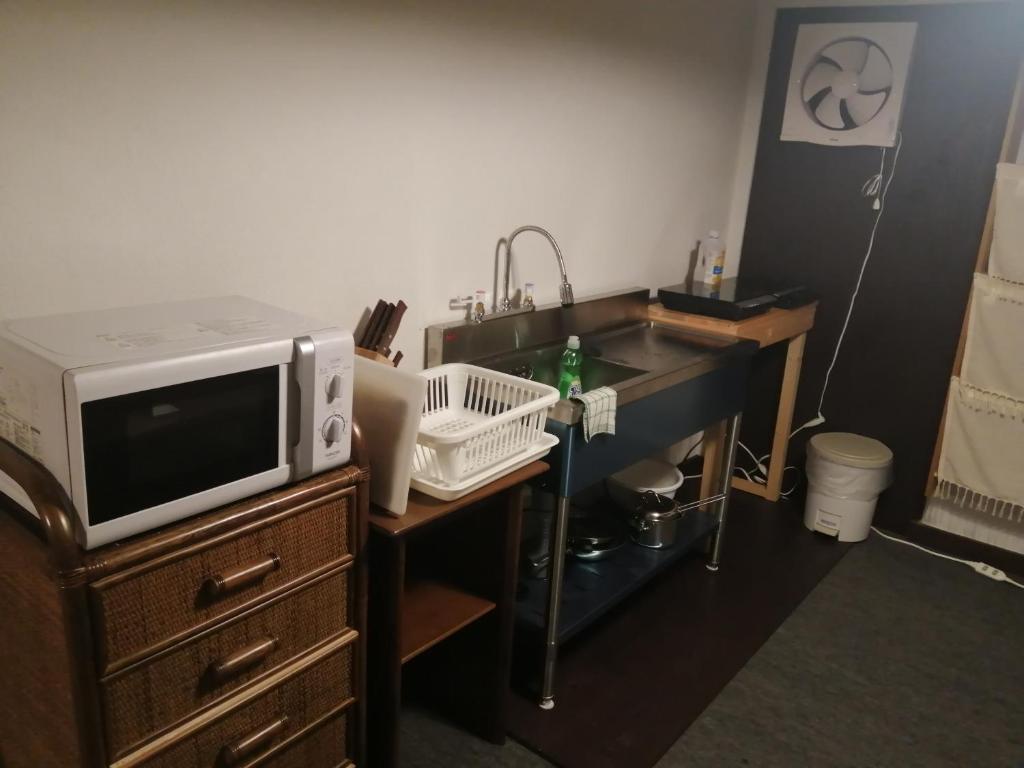 a kitchen with a microwave and a sink at Kusatsu Onsen Guesthouse Gyoten in Kusatsu