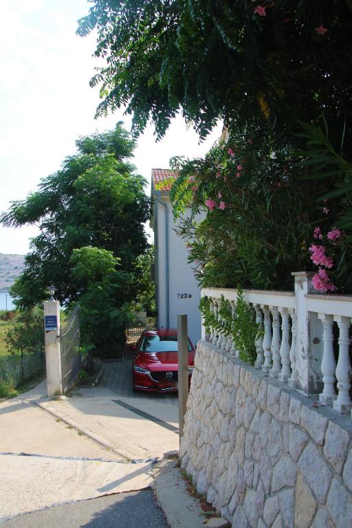 a car parked in front of a house with a wall at Apartments Maria Rab in Barbat na Rabu