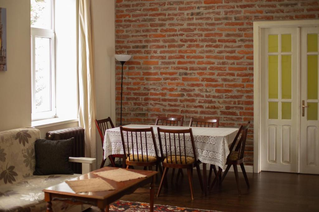 Old Lviv Apartment في إلفيف: غرفة طعام مع طاولة وكراسي وجدار من الطوب