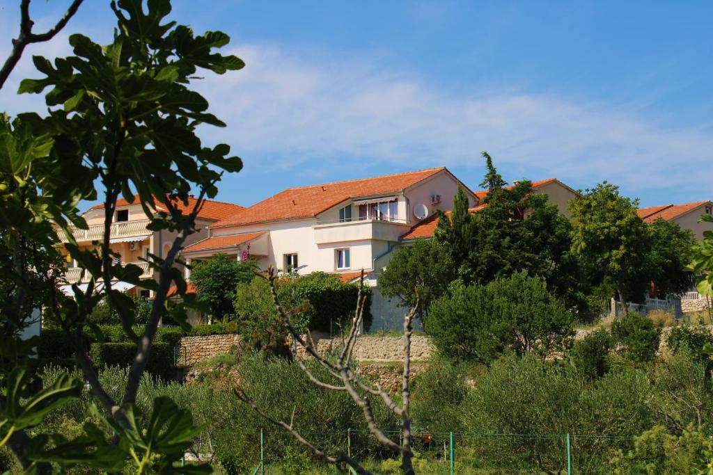 a house on a hill with trees and bushes at Apartments Maria Rab in Barbat na Rabu