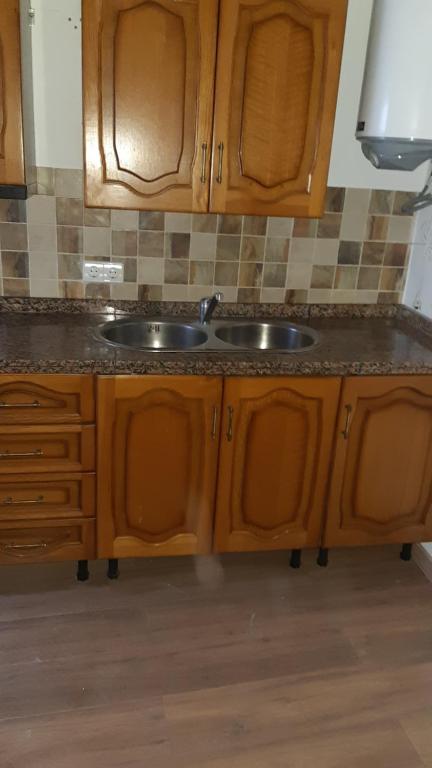 Una cocina con gabinetes de madera y un fregadero. en Casa Rocio, en Capileira