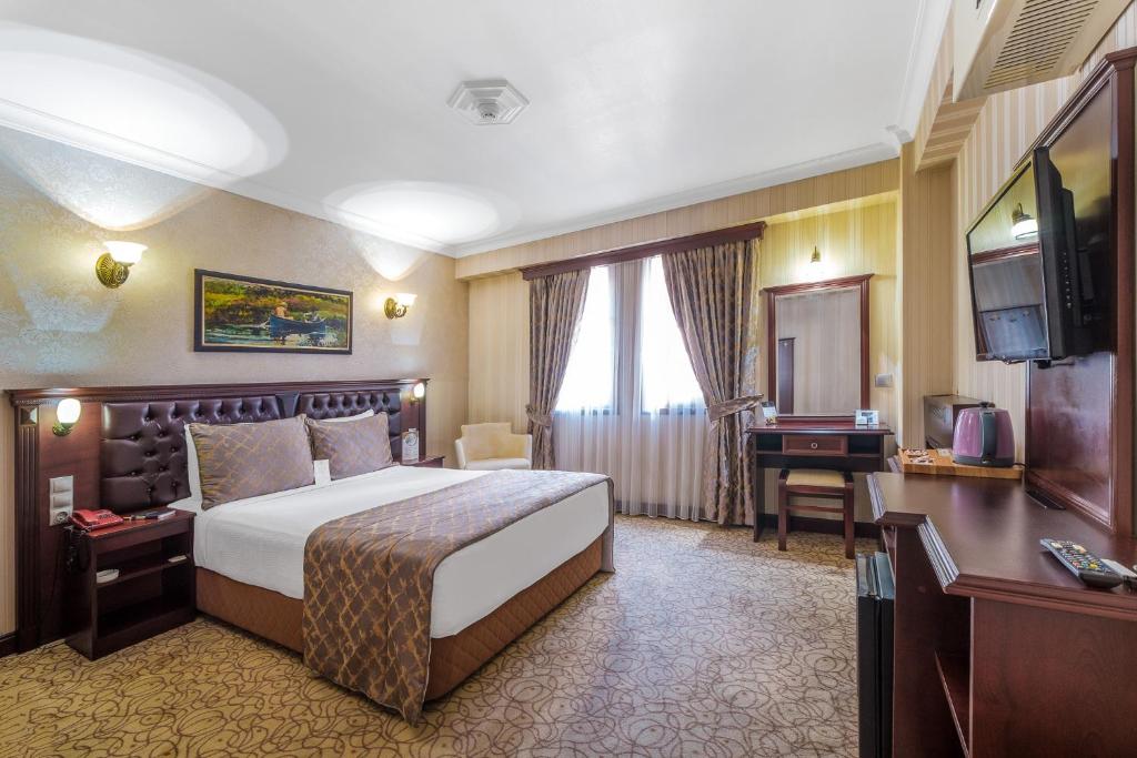 イズミールにあるオグラクチオグロ パーク ホテル ブティック ホテルのベッド、デスク、テレビが備わるホテルルームです。