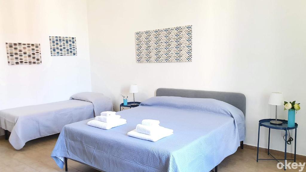 2 łóżka w pokoju z niebieską pościelą i ręcznikami w obiekcie Domus Garruba - Casa Vacanze Bari w mieście Bari