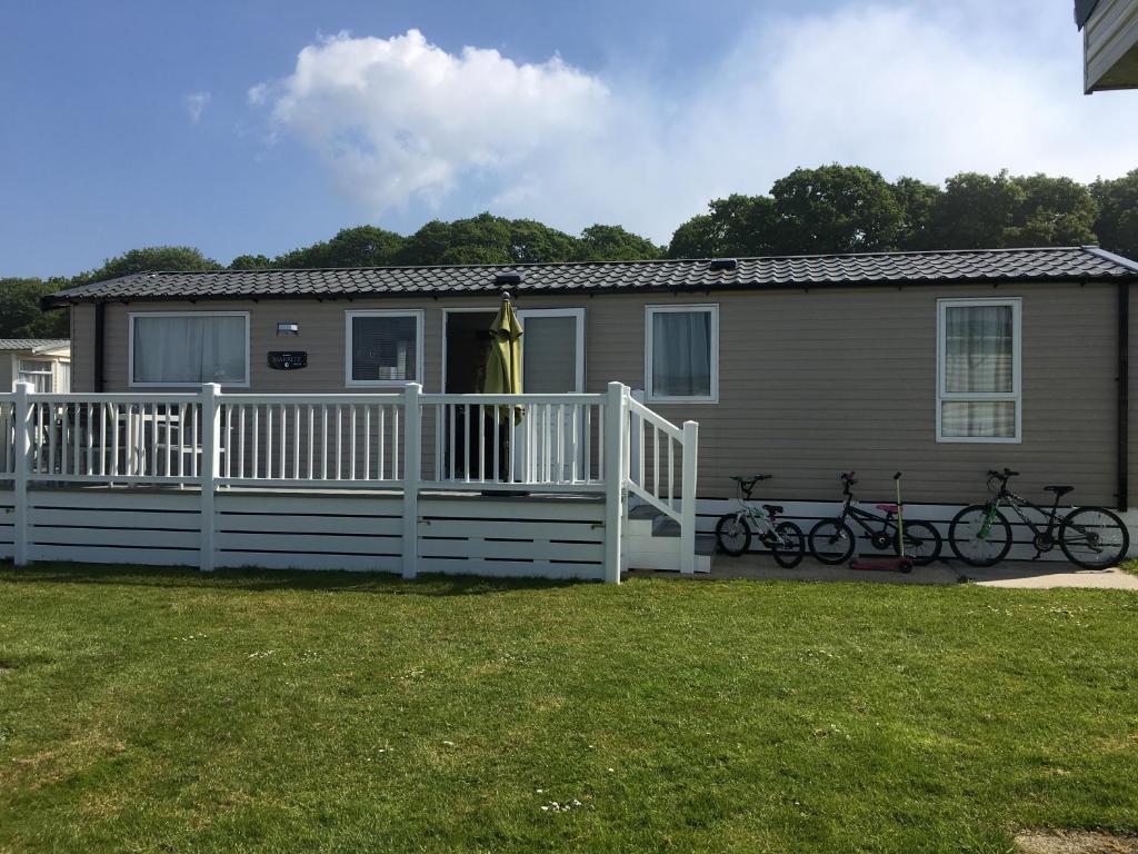 a house with a white fence and two bikes on a porch at 3 Bed Luxury Mobile Home Hoburne Park Christchurch in Christchurch