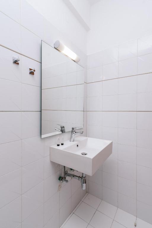 a white bathroom with a sink and a mirror at Amalia in Matala