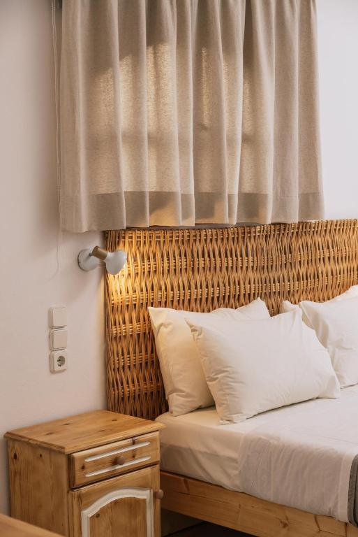 a bedroom with a bed with a wicker headboard and a table at Amalia in Matala