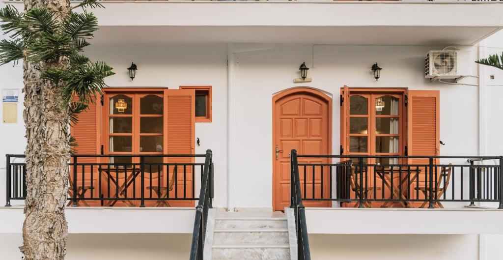 a house with orange doors and a palm tree at Amalia in Matala