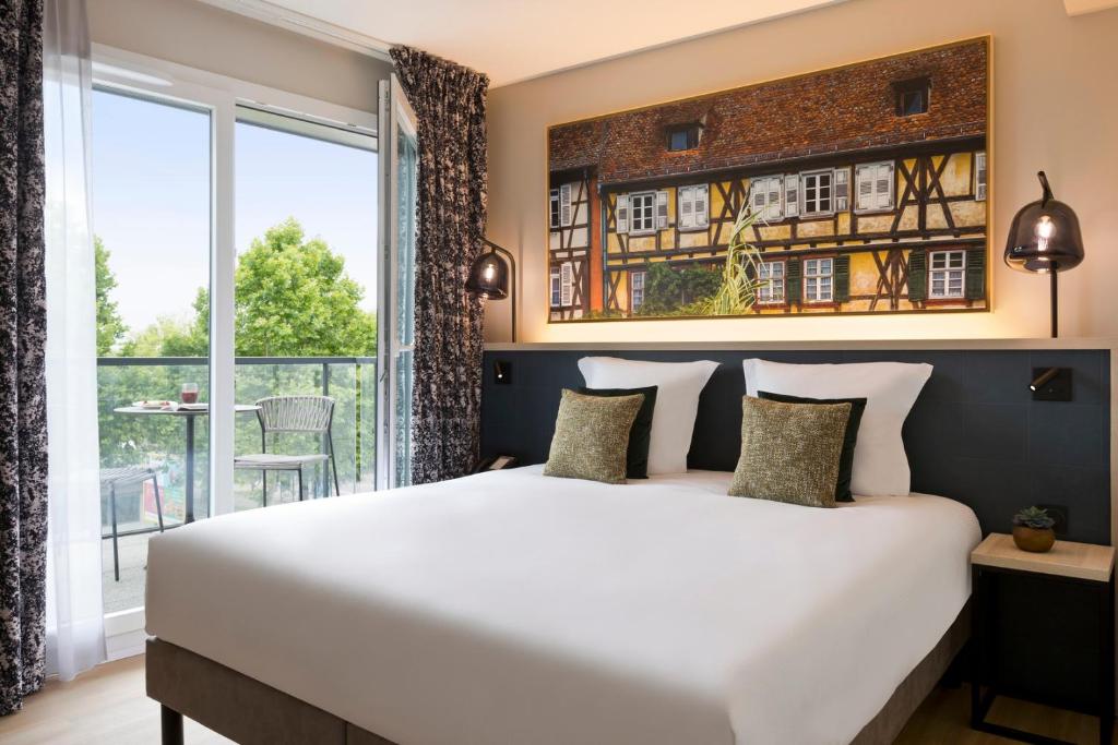 a bedroom with a large bed and a large window at Citadines Eurometropole Strasbourg in Strasbourg