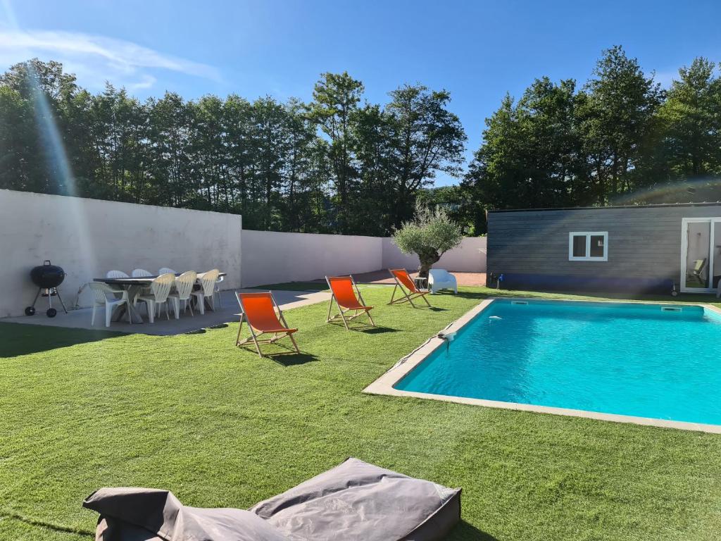 un patio trasero con piscina, sillas y mesa en Gîte des Vernizeaux, en Le Creusot