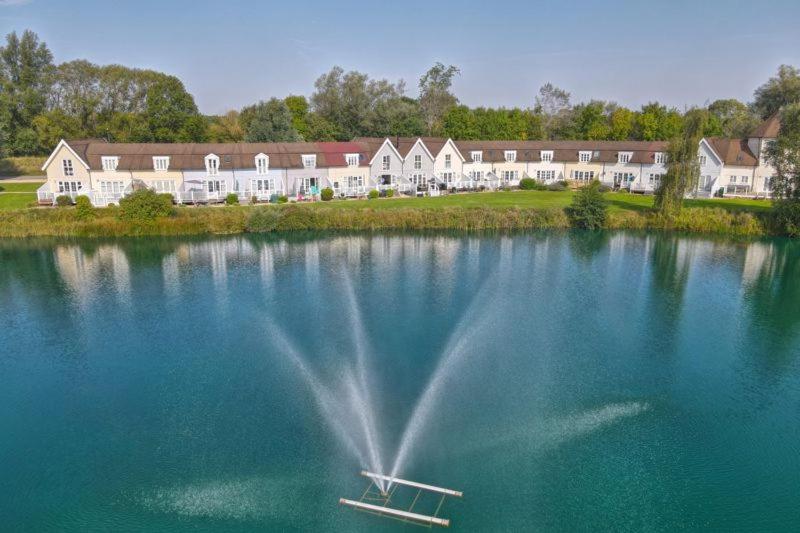 a large body of water with a house in the background at Lakehouse, 36 Isis Lake in Cirencester