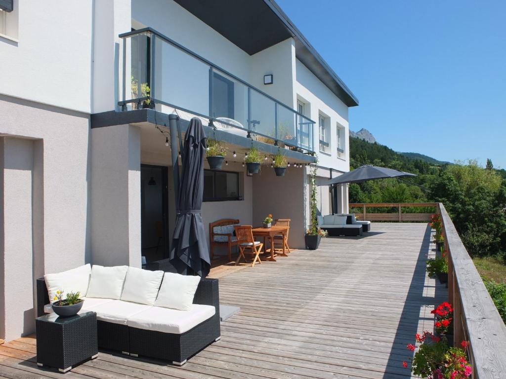 a deck with white furniture on a house at Katsoleil in La Bâtie-Neuve