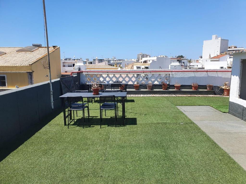 a table and chairs on a balcony with grass at Baixa Terrace Hostel in Faro