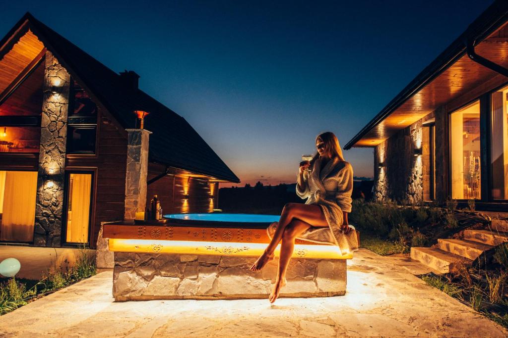 a woman sitting on a bench in front of a house at The View House Rabka-Zdrój WELLNESS & SPA in Rabka