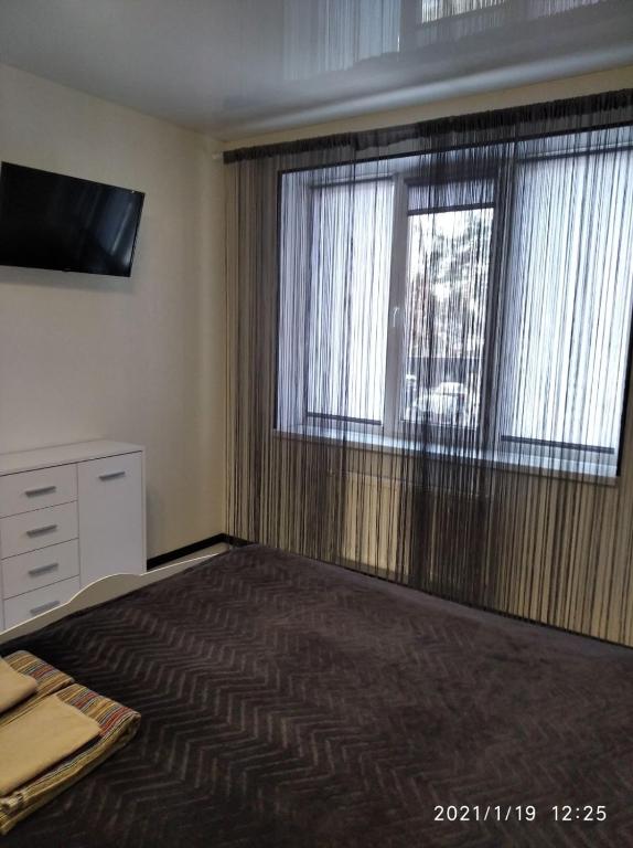 a bedroom with a bed and a large window at Ukrainska Apartment in Irpin