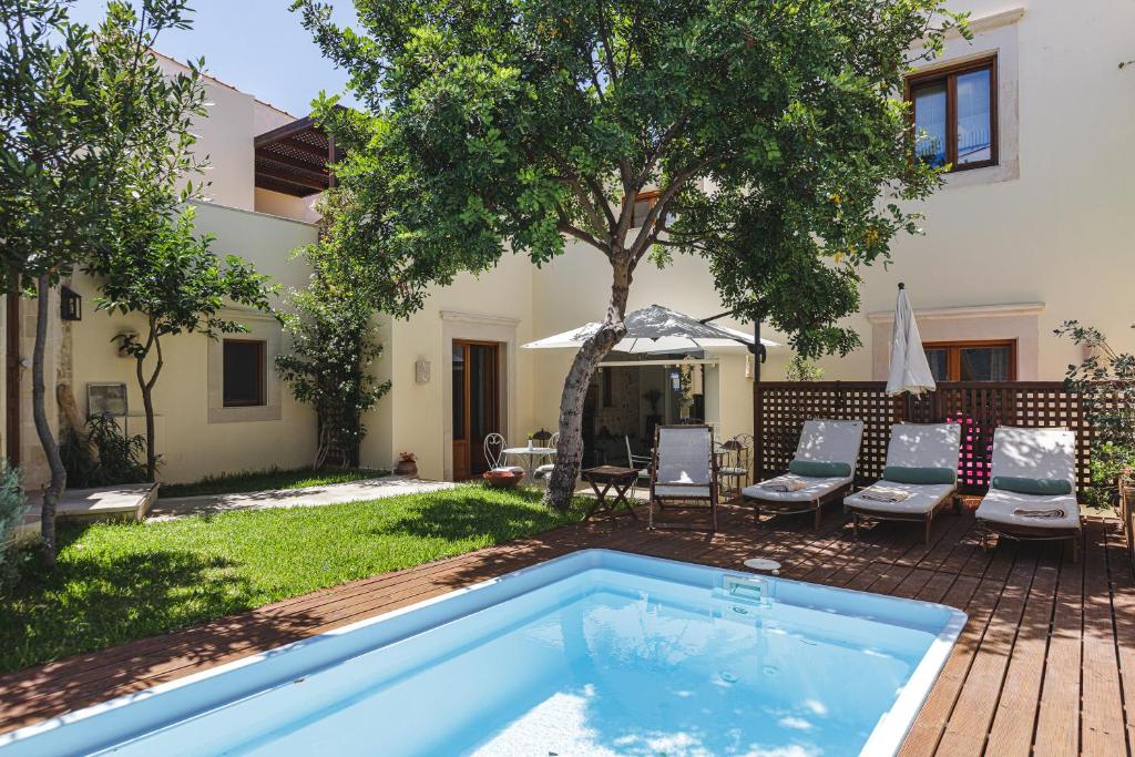 a pool in the yard of a house with chairs and a tree at Z Boutique Hotel in Panormos Rethymno