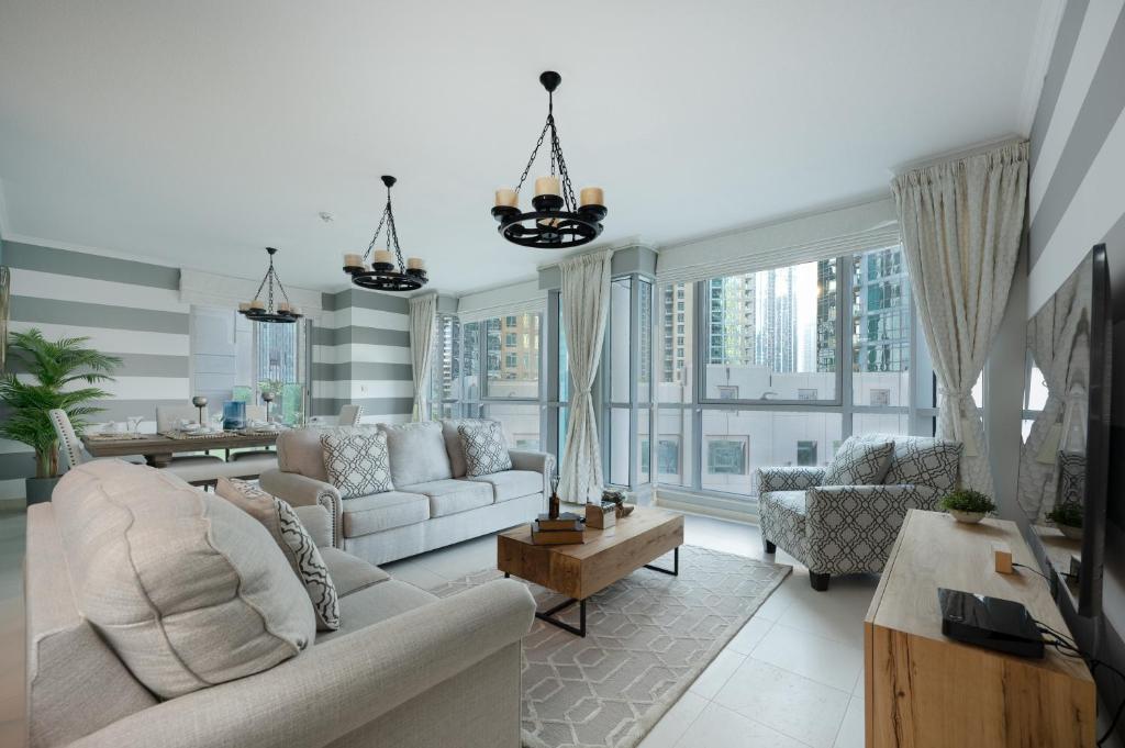 ein Wohnzimmer mit weißen Möbeln und großen Fenstern in der Unterkunft Burj Residence by Radiance Vacation Stays in Dubai