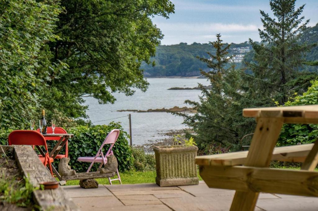 a patio with chairs and a view of a lake at Sea View - 2 Bedroom Cottage - Wisemans Bridge - Saundersfoot in Stepaside