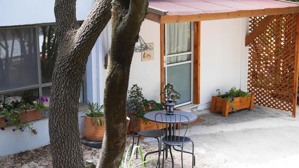 a patio with a table and chairs next to a tree at בין האלונים in H̱arashim