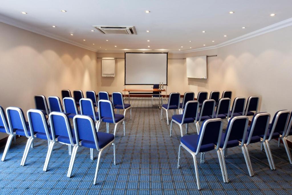a conference room with blue chairs and a screen at Holiday Inn - Glasgow Airport by IHG in Paisley