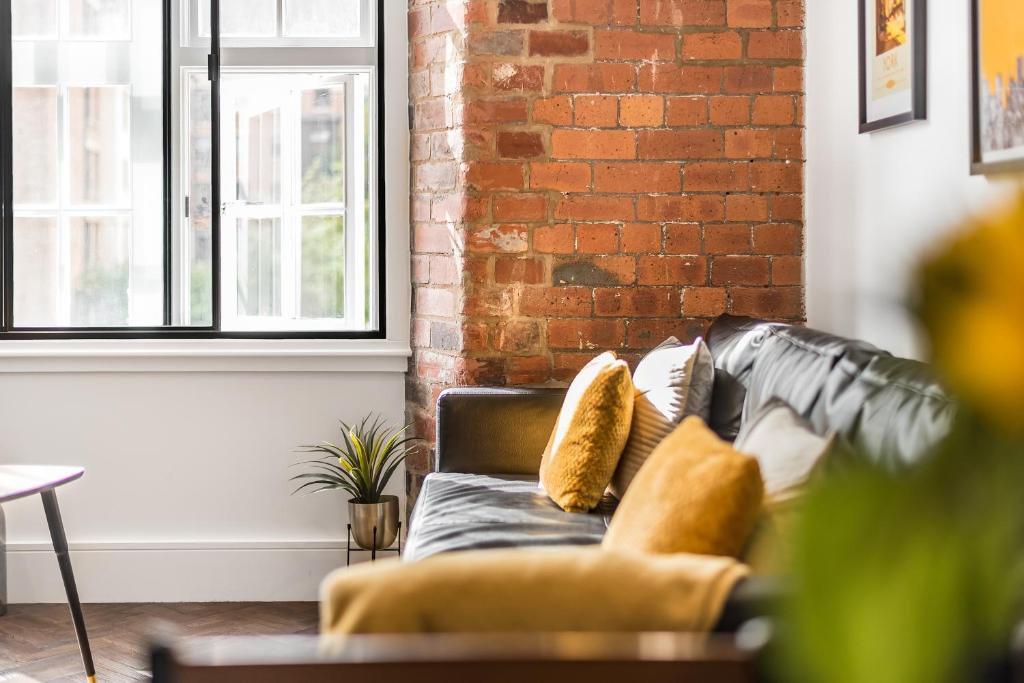 um sofá numa sala de estar com uma parede de tijolos em Chic one bed apartment- City Living in converted Cocoa Warehouse York PARKING em York
