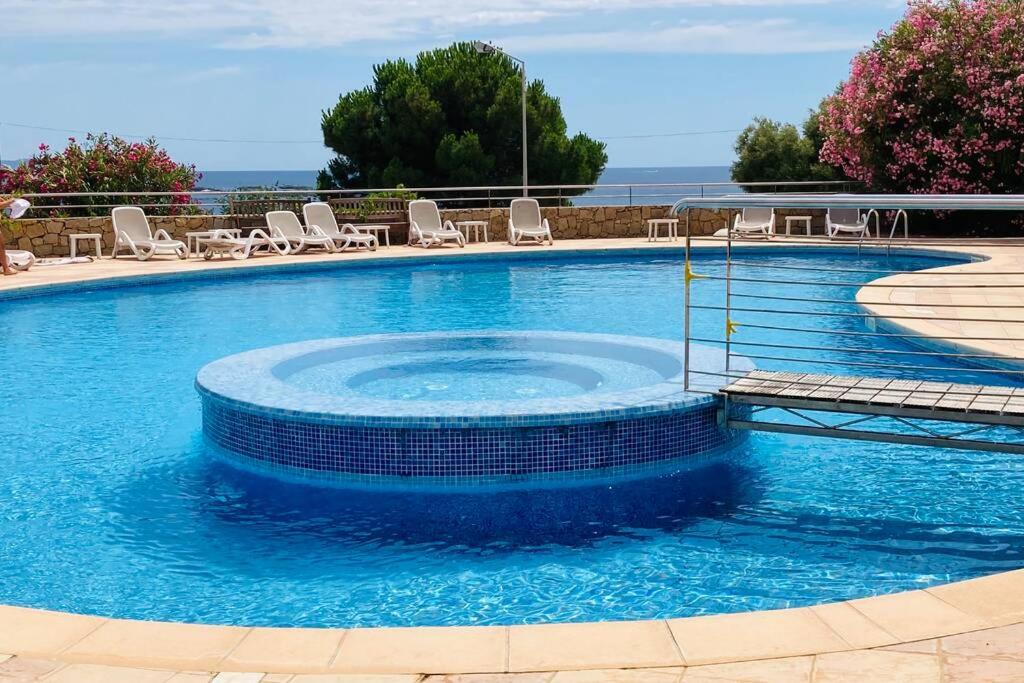 uma grande piscina com cadeiras e água azul em Appartement VAIANA avec piscine en bord de mer em Ajaccio