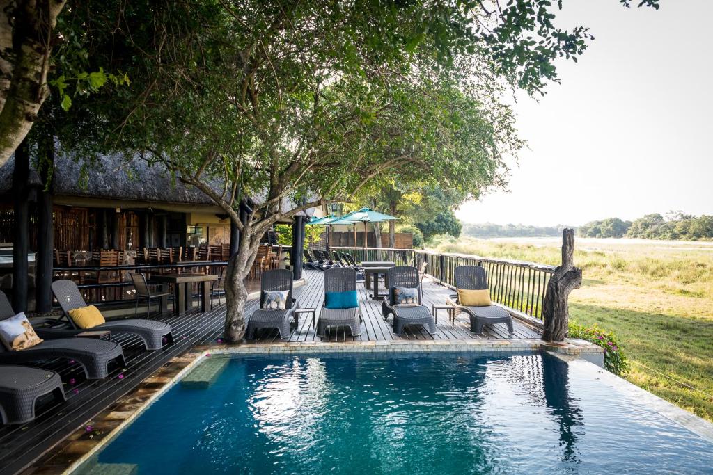 einen Pool mit Liegestühlen und einem Tisch in der Unterkunft Umkumbe Safari Lodge Riverside in Skukuza