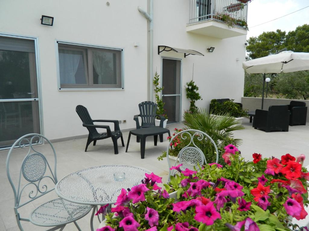 een patio met een tafel, stoelen en bloemen bij A Casa di Anna - Locazione Turistica - in Matera