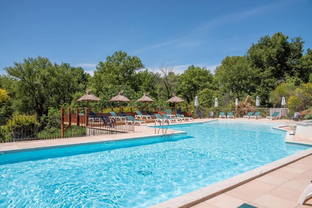 a pool at a resort with chairs and umbrellas at Domaine des Bridoux Village de Gîtes in Mirabel-aux-Baronnies