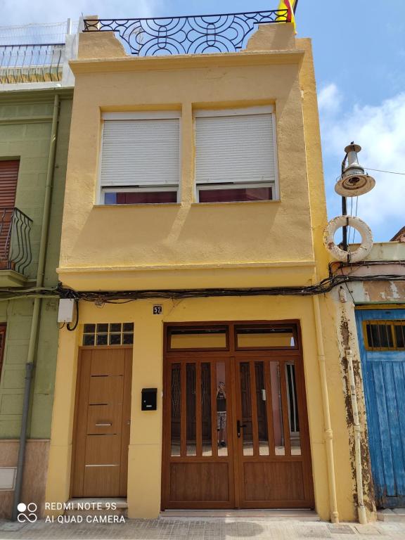 uma casa amarela com portas e janelas de madeira em Apartamento vinamar em Vinarós
