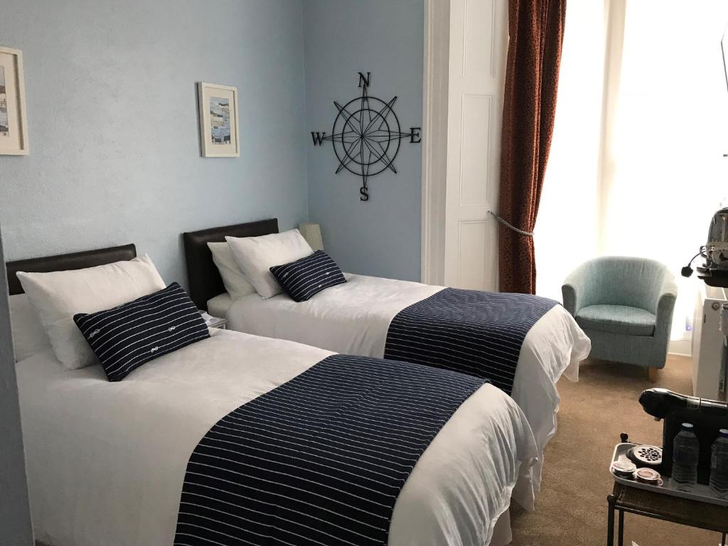 een slaapkamer met 2 bedden en een wiel aan de muur bij Highlea Guest House in Weston-super-Mare