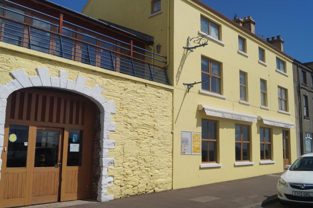 żółty budynek z drzwiami i samochodem zaparkowanym przed budynkiem w obiekcie The Narrows w mieście Portaferry