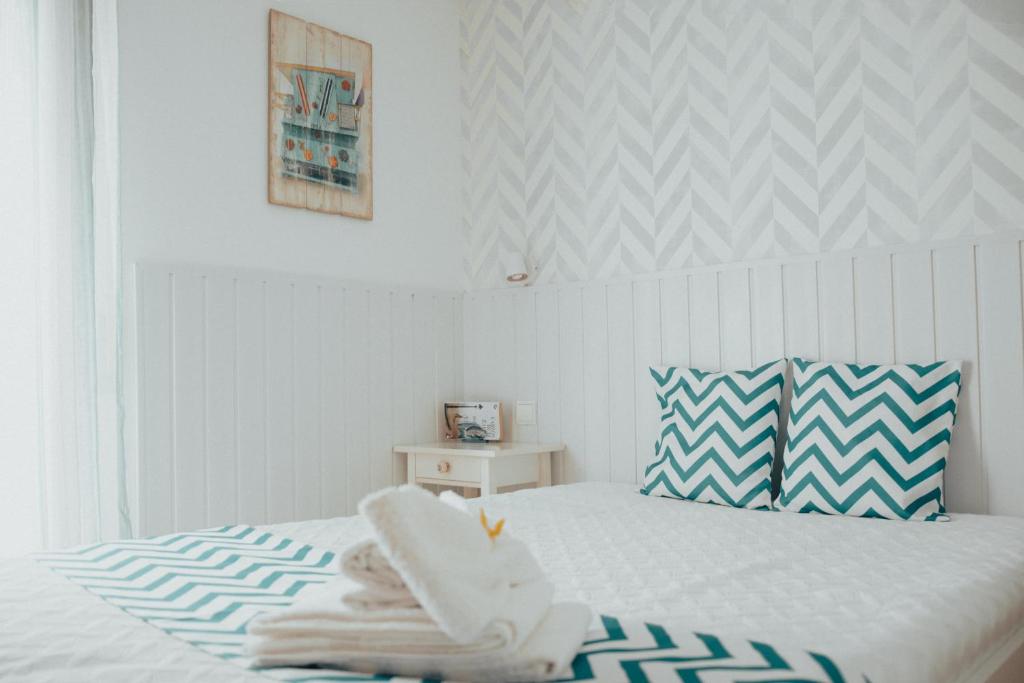 um quarto com uma cama branca e uma almofada azul e branca em Camy House em Nazaré