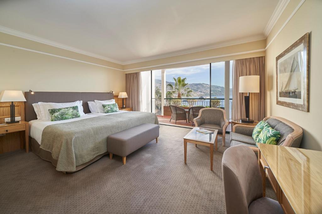 a hotel room with a bed and a living room at The Cliff Bay - PortoBay in Funchal
