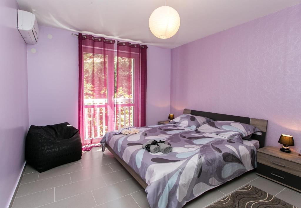 a bedroom with purple walls and a bed and a window at Apartment Lapad Bay in Dubrovnik