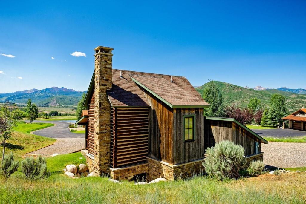 a log home with a chimney on a field at Chaparral Aspen Ranch Cabin in Woody Creek
