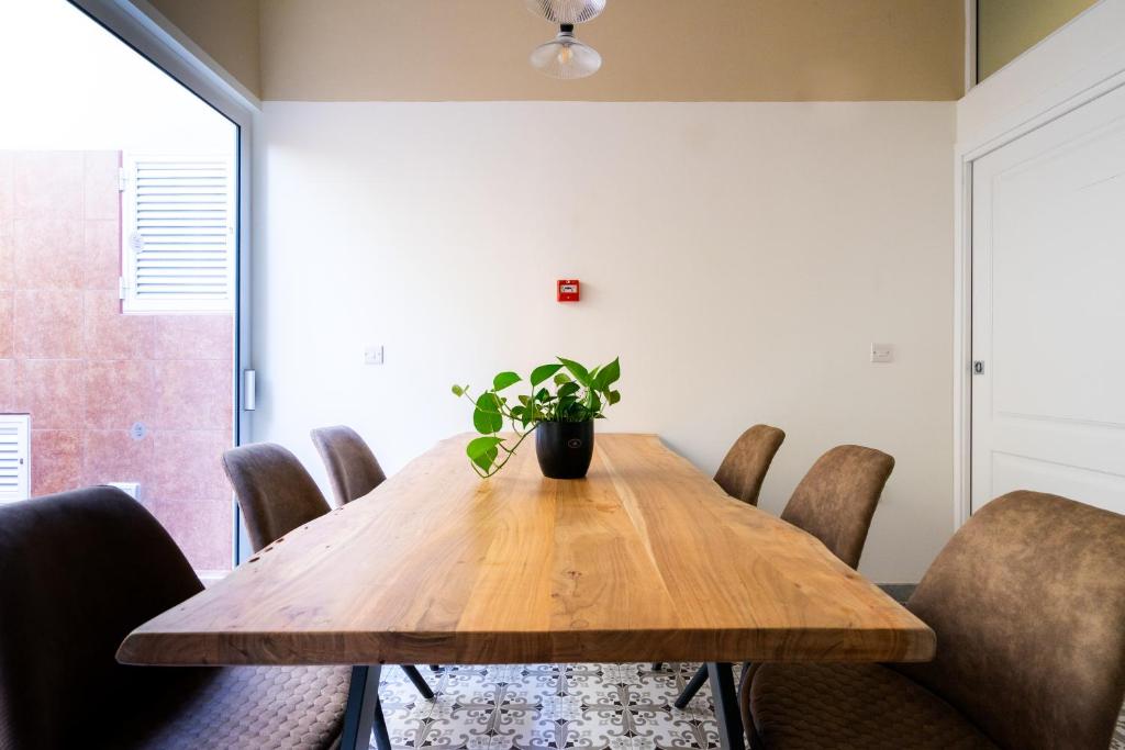 a dining room table with chairs and a potted plant at Lady Todd in Sliema
