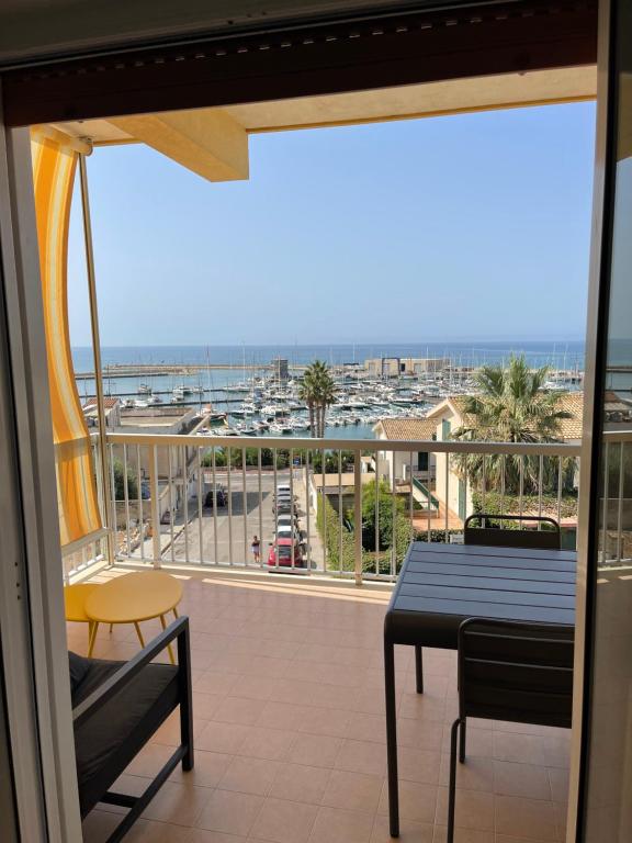 een balkon met een tafel en stoelen en uitzicht op de oceaan bij La vista sul porto in Marina di Ragusa