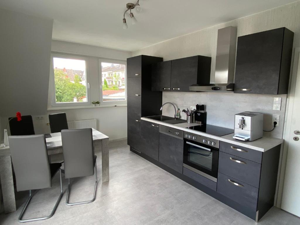 une cuisine avec des armoires noires et une table à manger dans l'établissement Helle moderne Ferienwohnung, Nähe Koblenz am Rhein, à Weitersburg