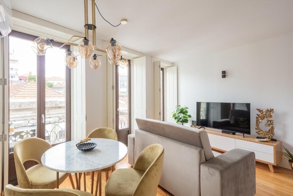 a living room with a table and chairs and a tv at Douro Golden Studio in Porto