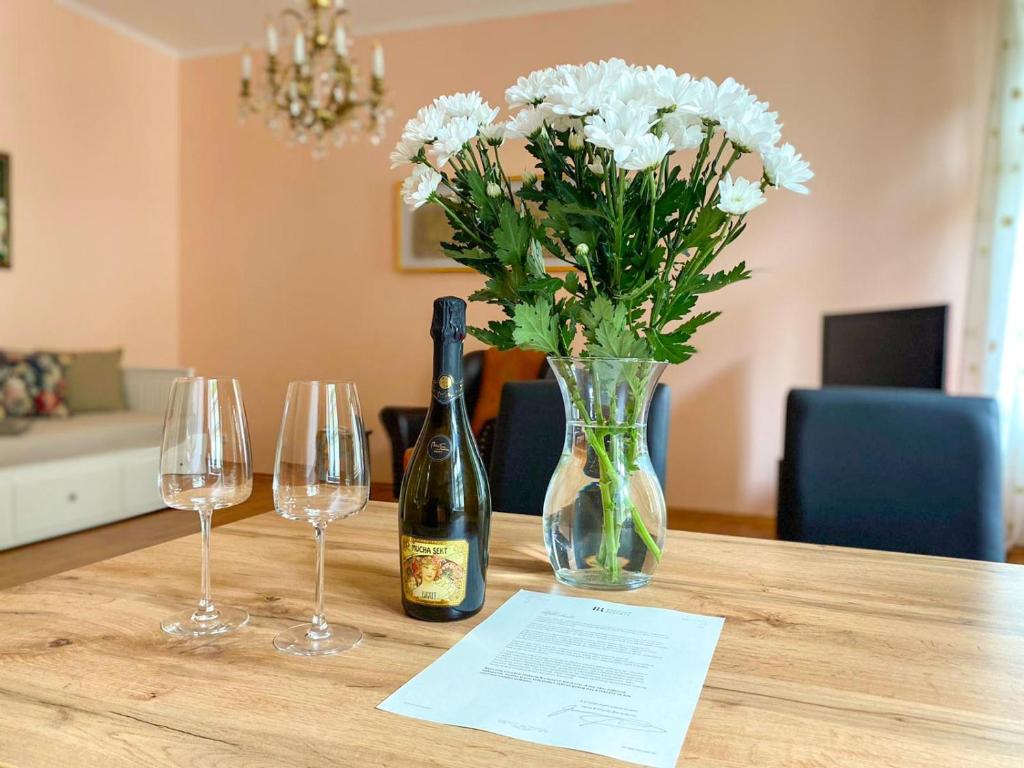 a table with a bottle of wine and two wine glasses at Apartmá Marie 1880 in Karlovy Vary