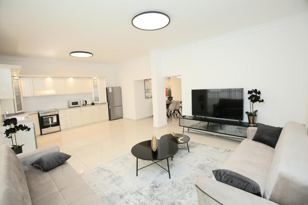 City center luxury apartment in Netanya في نتانيا: غرفة معيشة بيضاء مع أريكة وطاولة