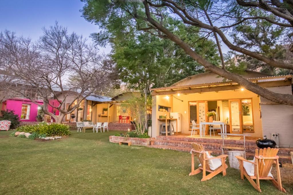 a house with a yard with chairs and tables at Aasvoelkrans Guest Farm in Montagu