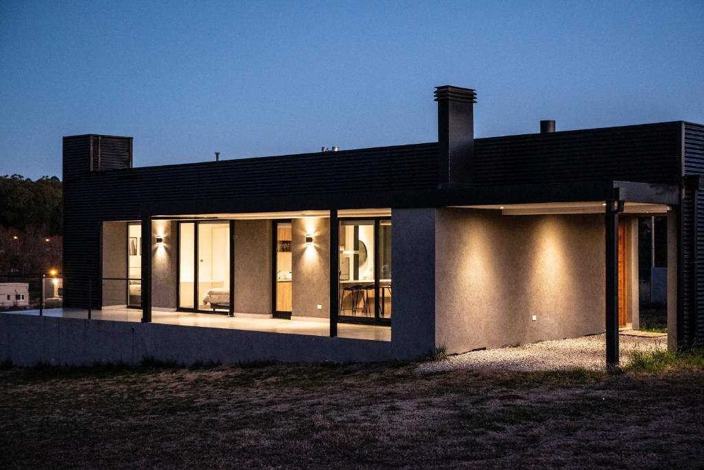 een huis met een zwart dak en grote ramen bij Del Cerro Alquiler Temporario in Tandil