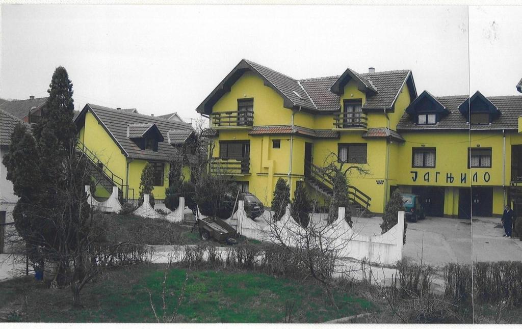 ein gelbes Haus mit einem Zaun davor in der Unterkunft UTR Jagnjilo 1986 in Raška