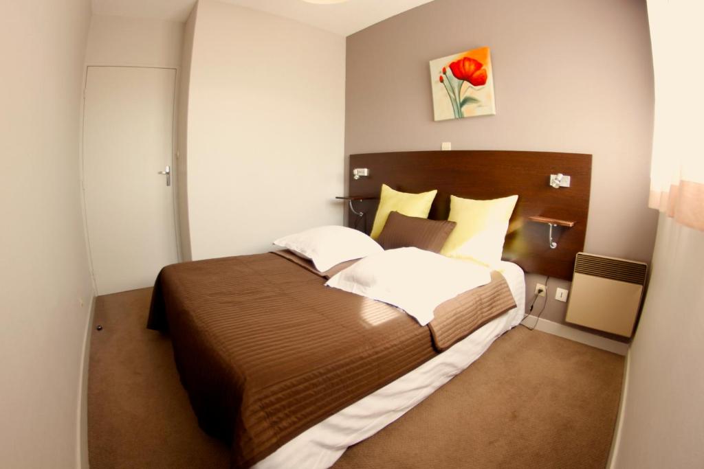 een slaapkamer met een groot bed in een kamer bij Appart'hotel Les Palatines in Saint-Étienne