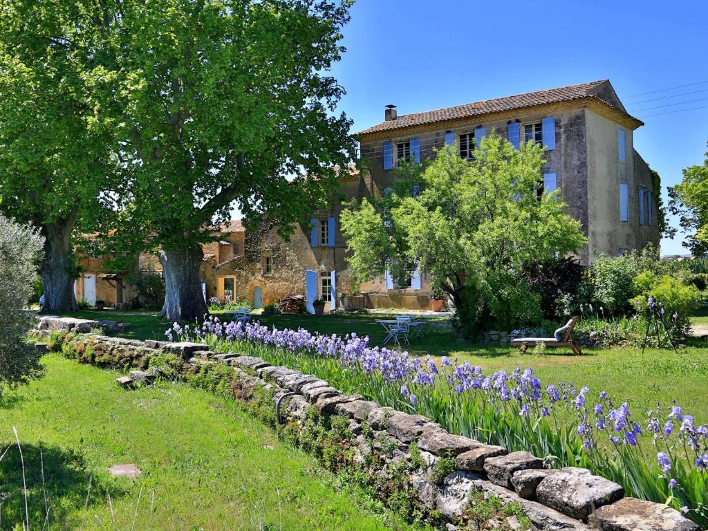 un jardin avec des fleurs violettes en face d'un bâtiment dans l'établissement Domaine la Carraire, à Lauris